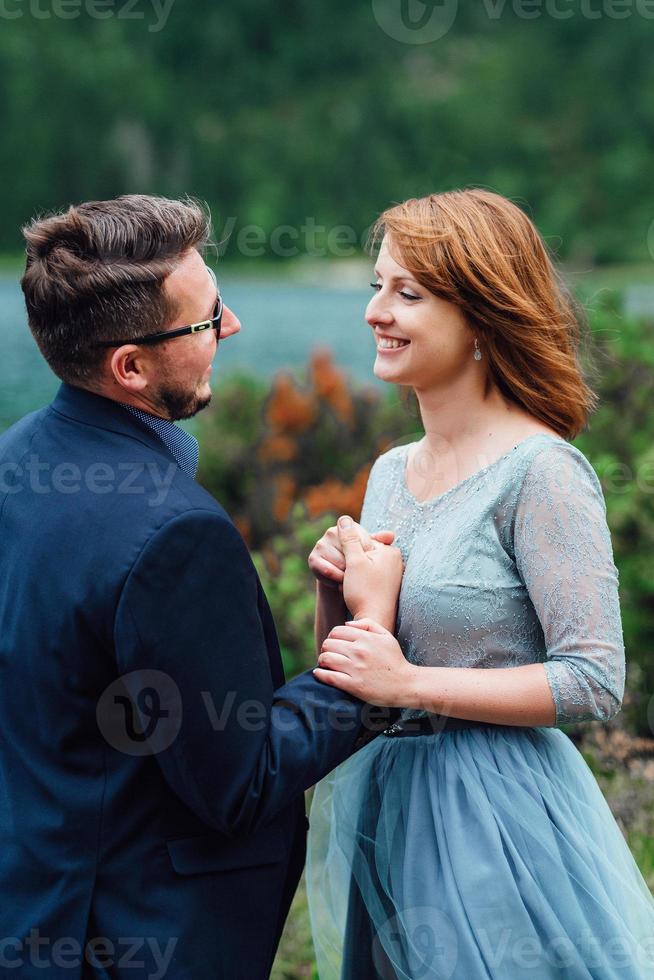 Young couple on a walk near the lake surrounded by the mountains photo