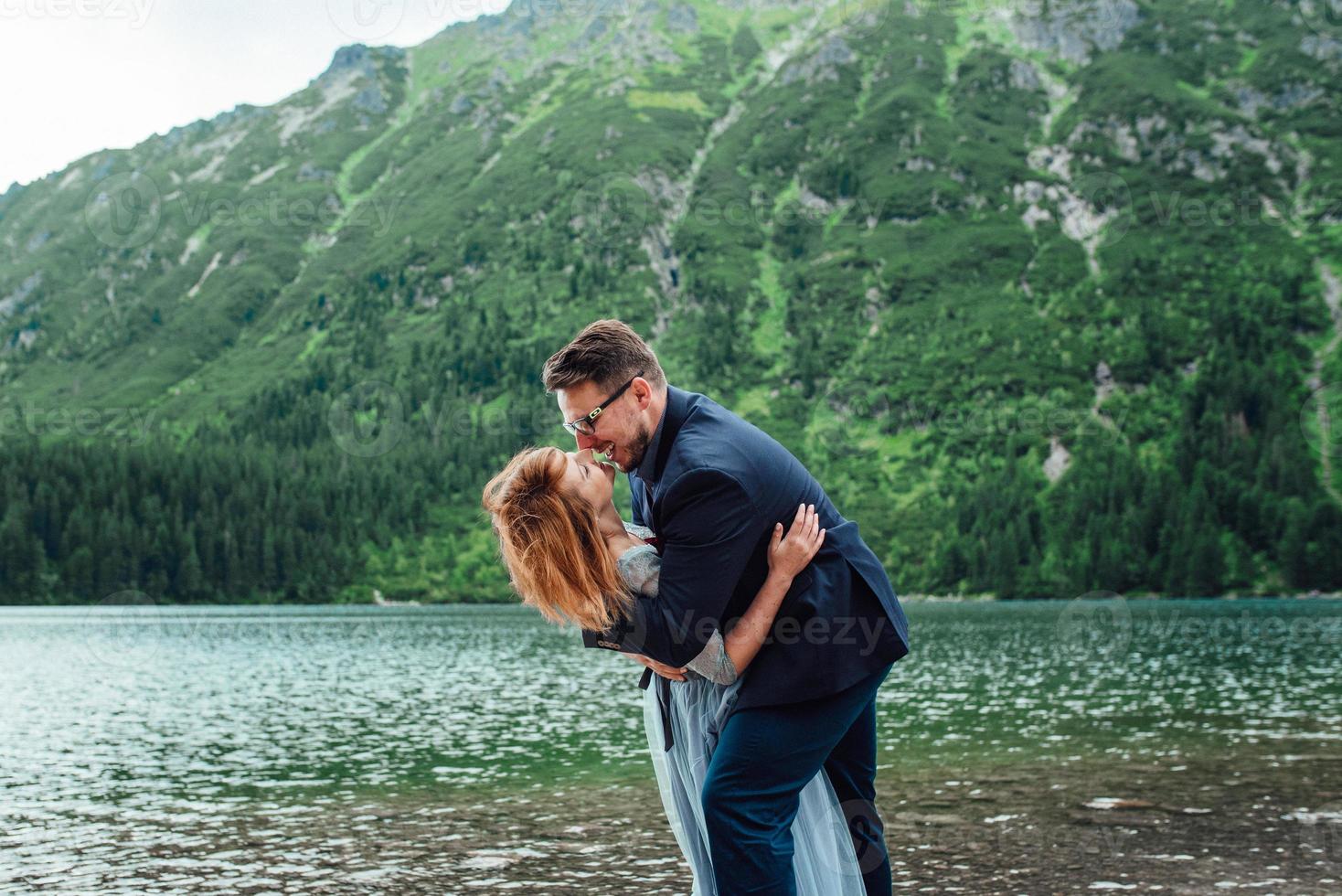 pareja joven en un paseo cerca del lago rodeado por las montañas foto