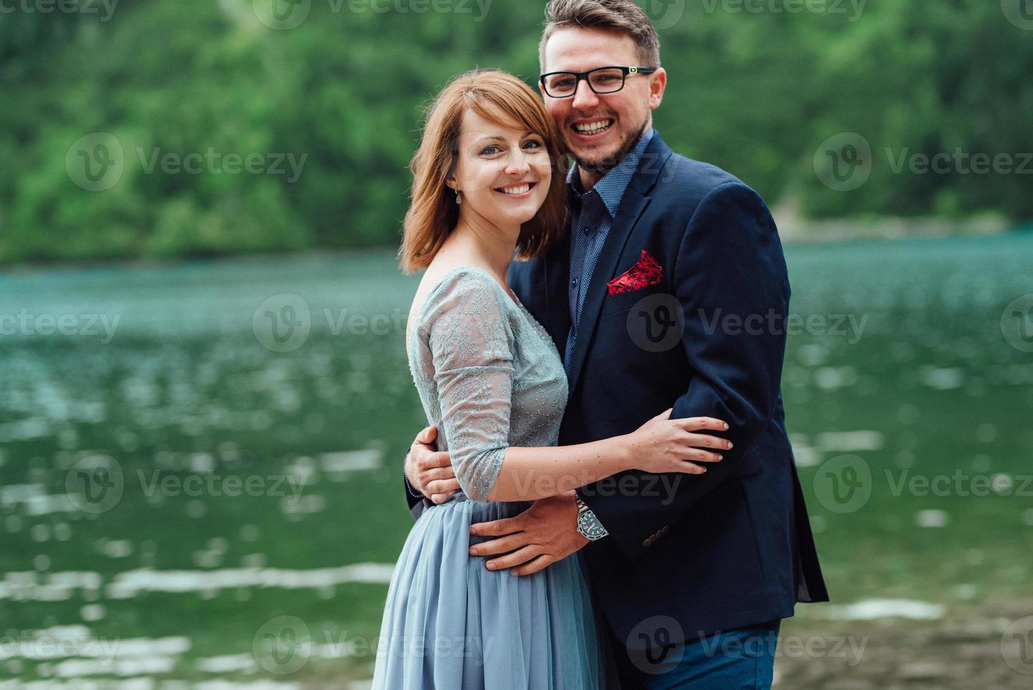 Young couple on a walk near the lake surrounded by the mountains photo