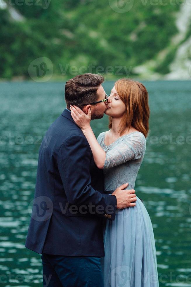 Young couple on a walk near the lake surrounded by the mountains photo