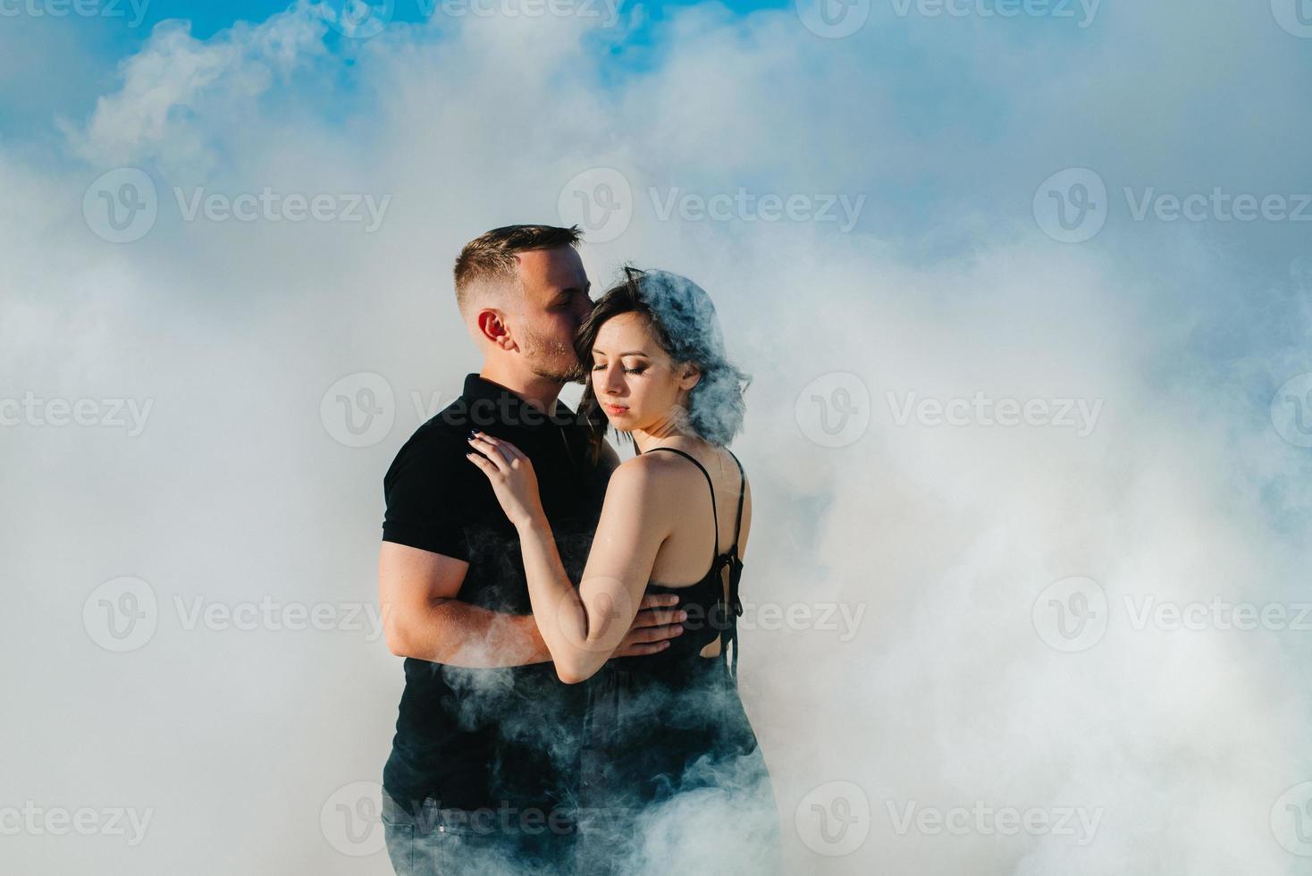 Guy and a girl in black clothes hug inside white smoke photo