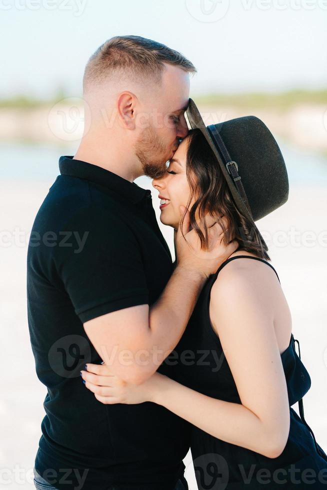 Young couple a guy and a girl with joyful emotions in black clothes walk through the white desert photo