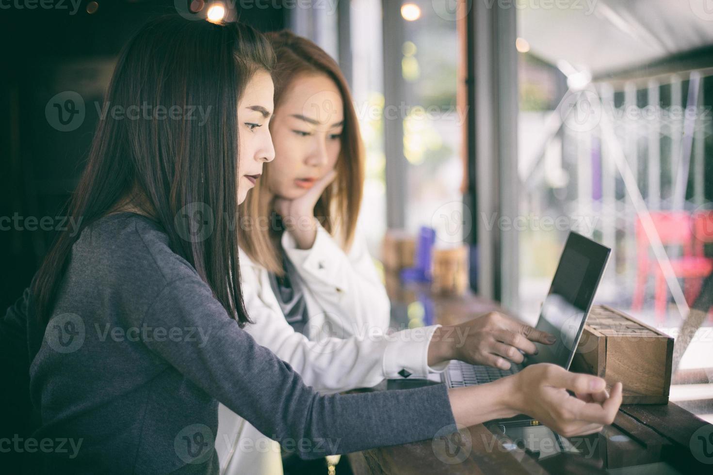 Two Asian business women working on a laptop photo
