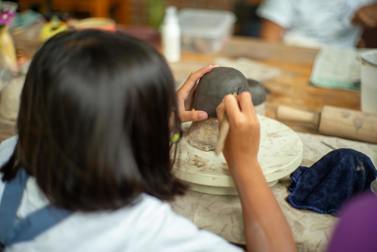 Primer trabajo de arcilla en el modelo de yeso con movimiento borroso manos de aprendizaje de los estudiantes en el aula del taller foto