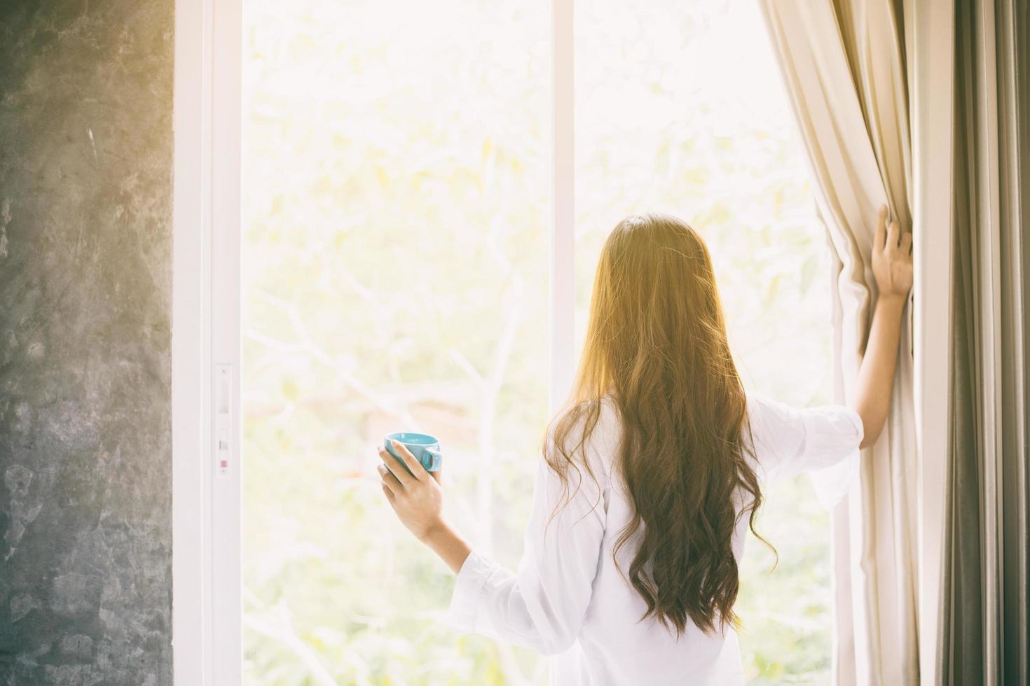 mujeres asiáticas tomando café y mirando por la ventana foto