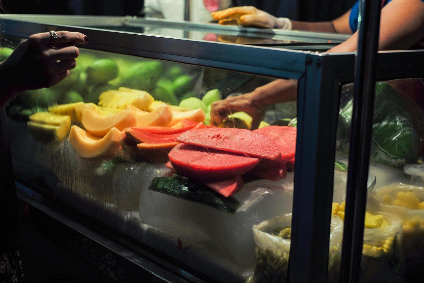 Various fruits in a glass cooler at a street food stall at a night market. photo