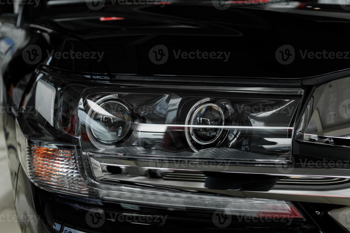 Headlight of modern prestigious black car close-up photo