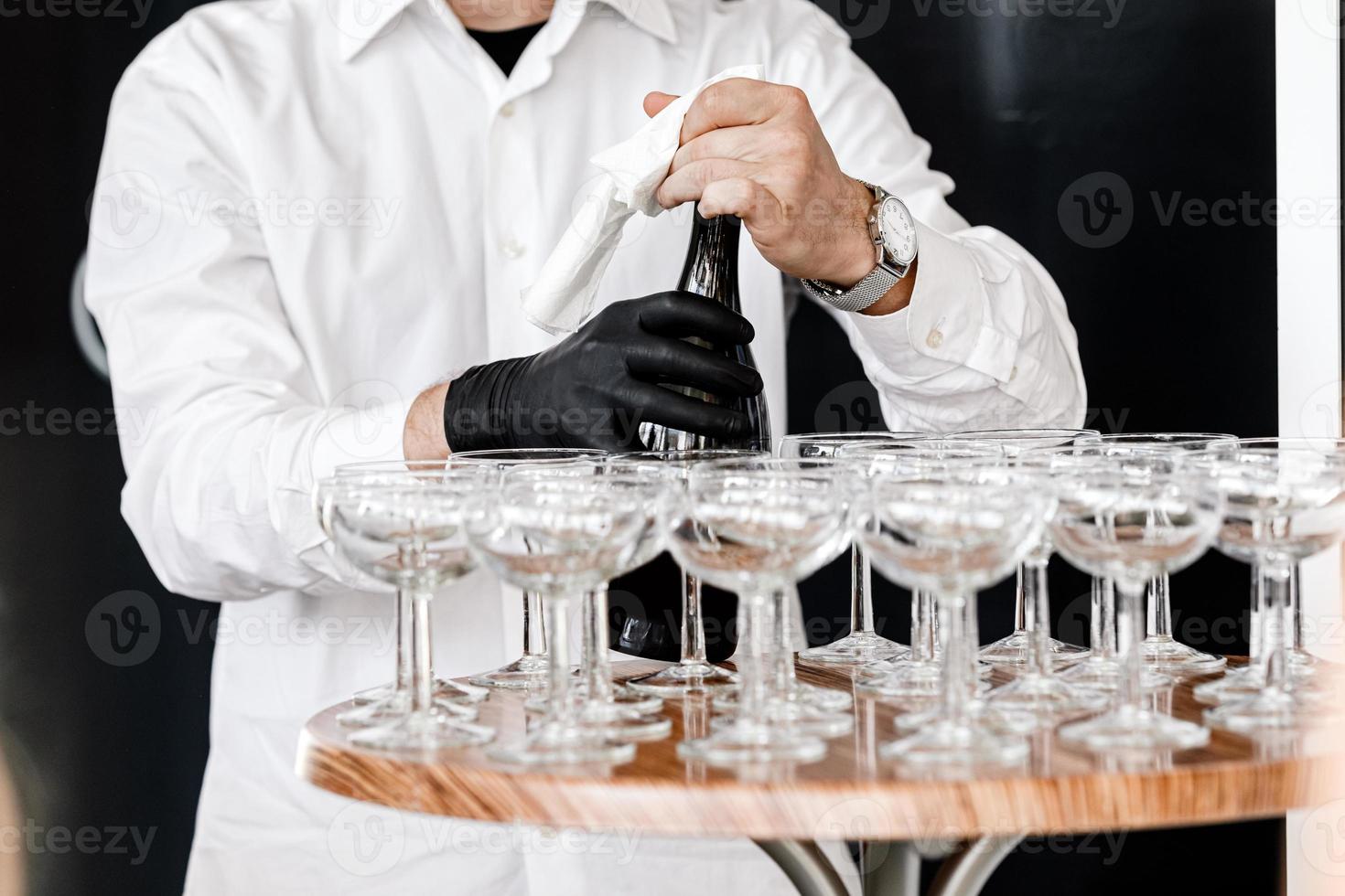The waiter opens a bottle of champagne photo
