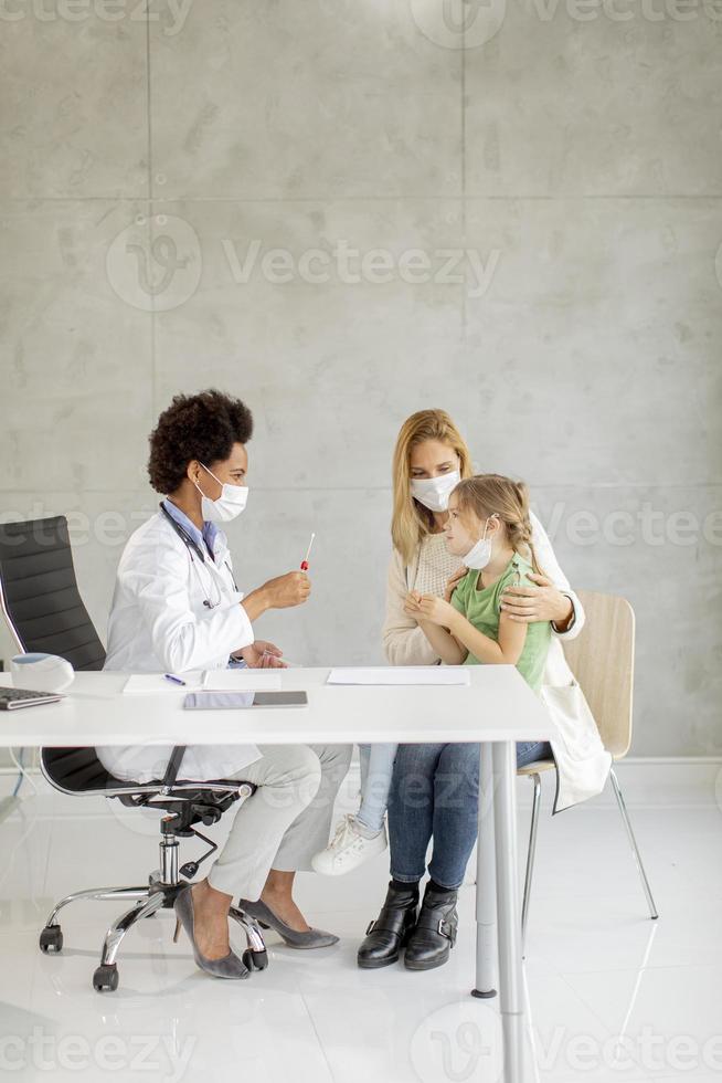 madre con hija pequeña en la oficina del pediatra foto