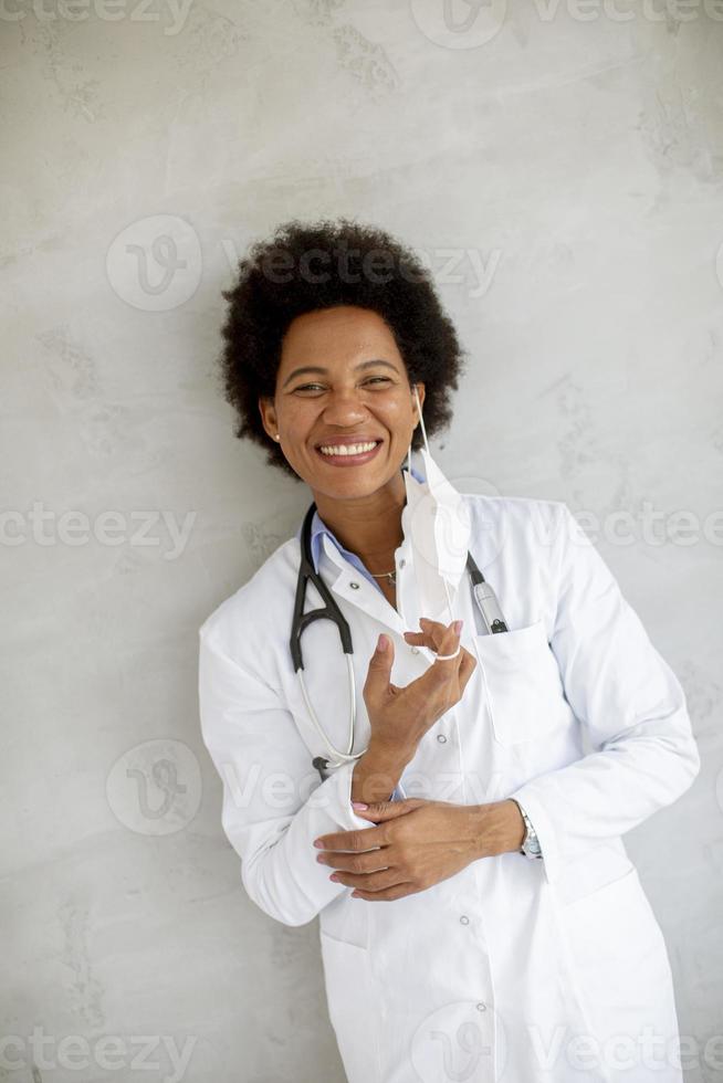 Doctor leaning against a wall and taking off mask photo