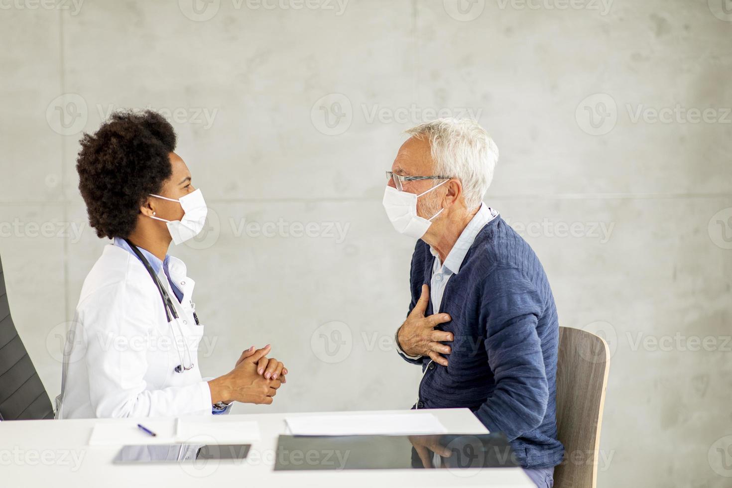 Mature man discussing chest pain with doctor photo