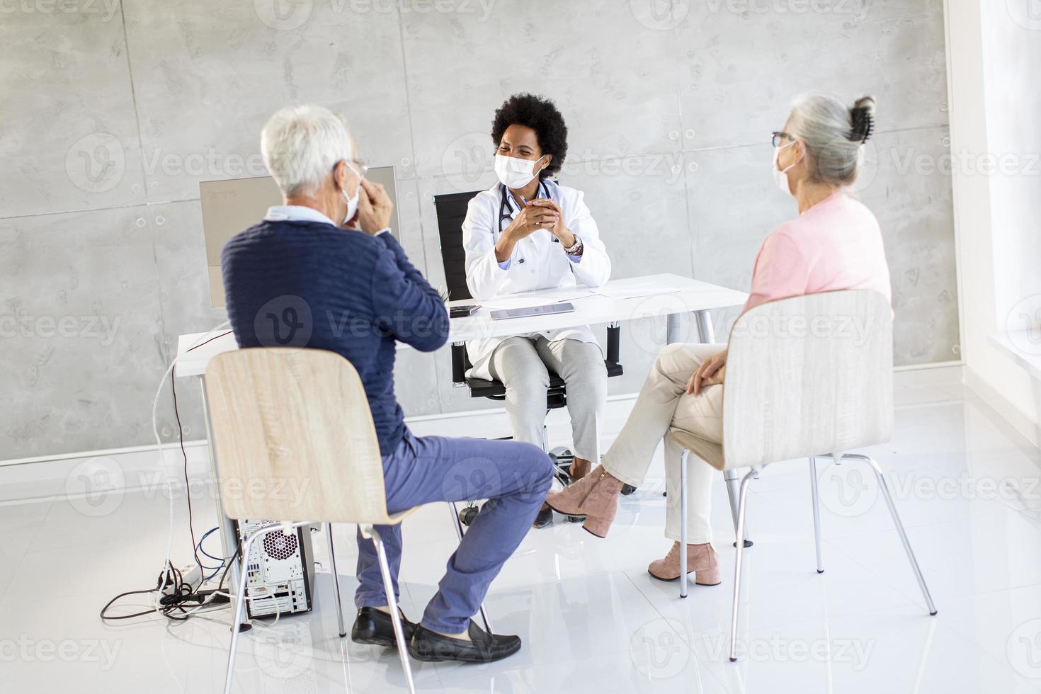 Masked mature couple in doctor's office photo