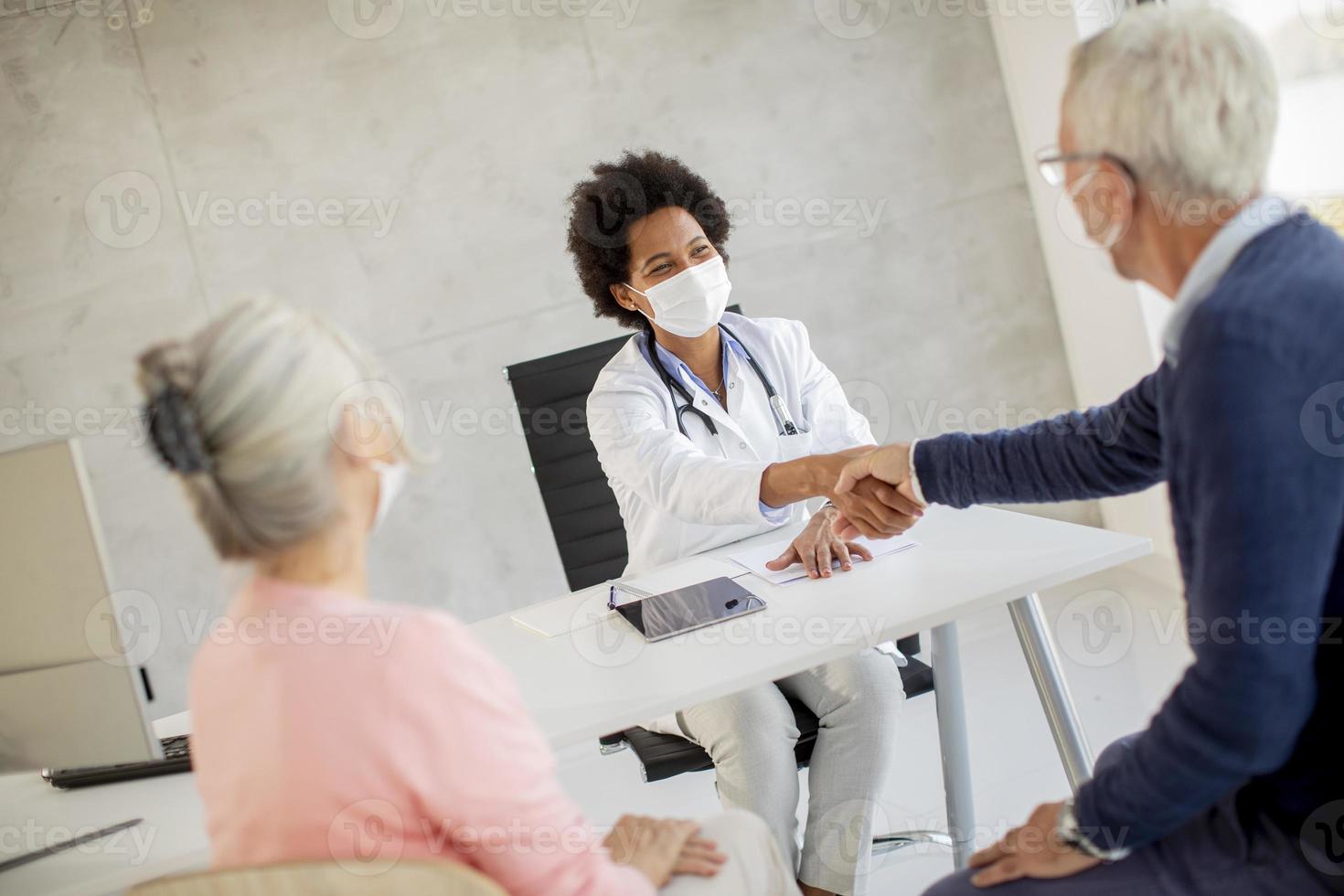 doctor hablando con una pareja madura enmascarada foto