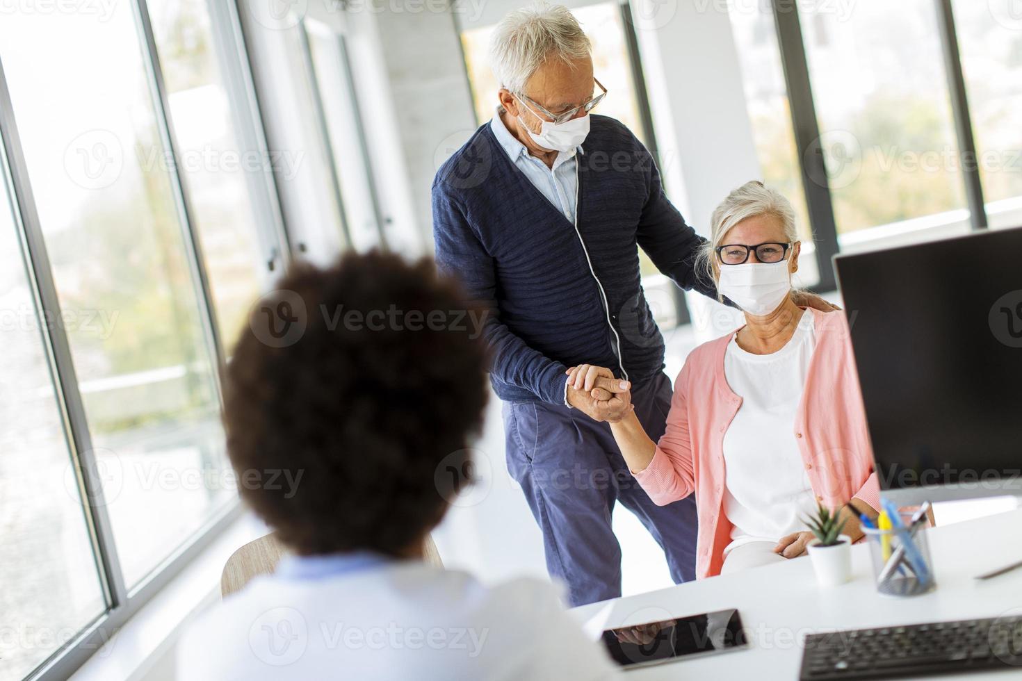 Hombre maduro consolando a su esposa en el consultorio del médico foto