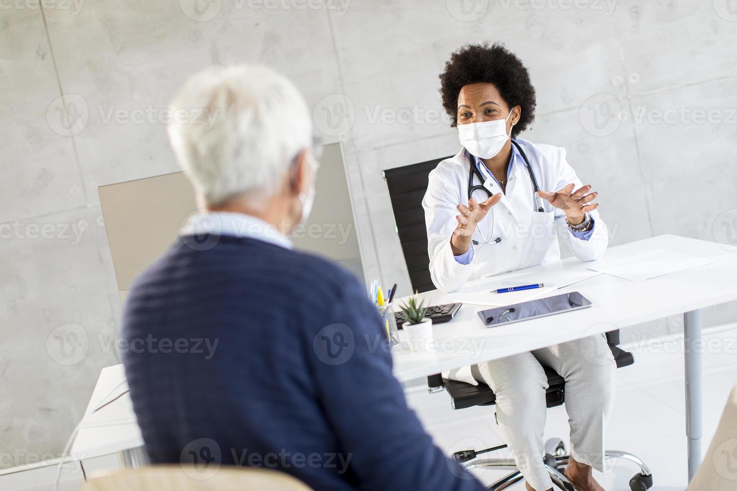 Doctor speaking to mature man in masks photo