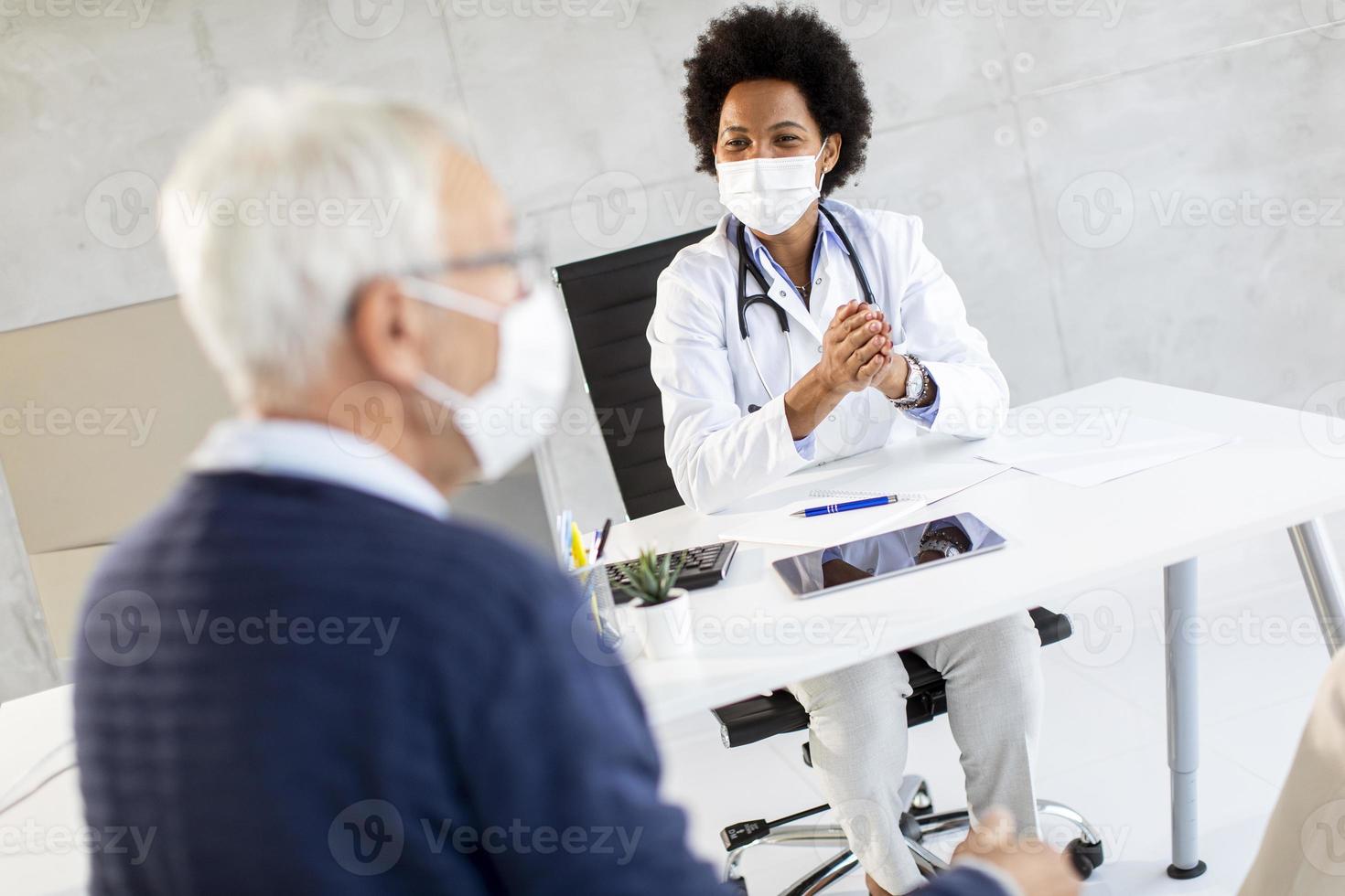 Masked mature man receiving news from doctor photo