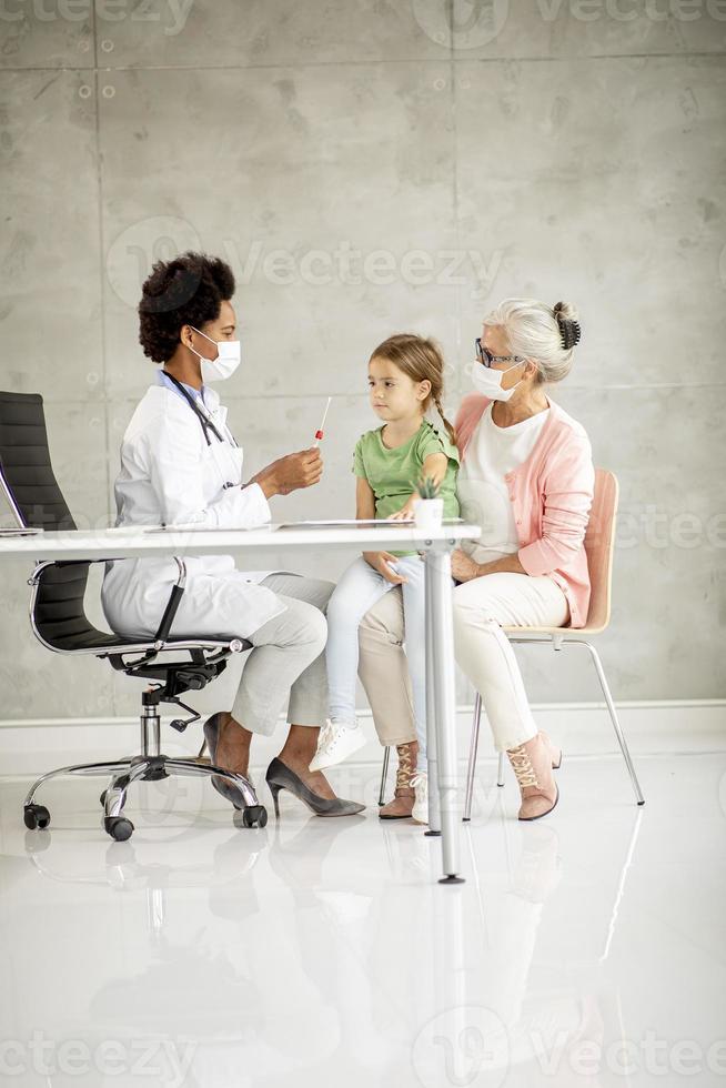 Vertical view of masked grandmother with granddaughter at doctor's office photo