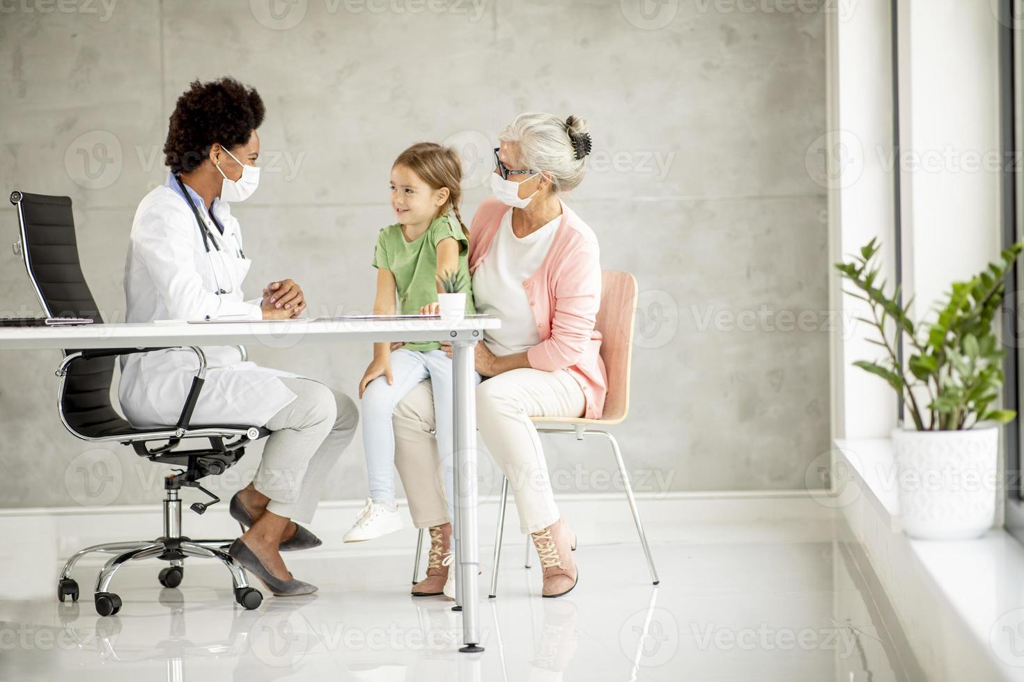 Pediatrician examining girl with grandmother present photo