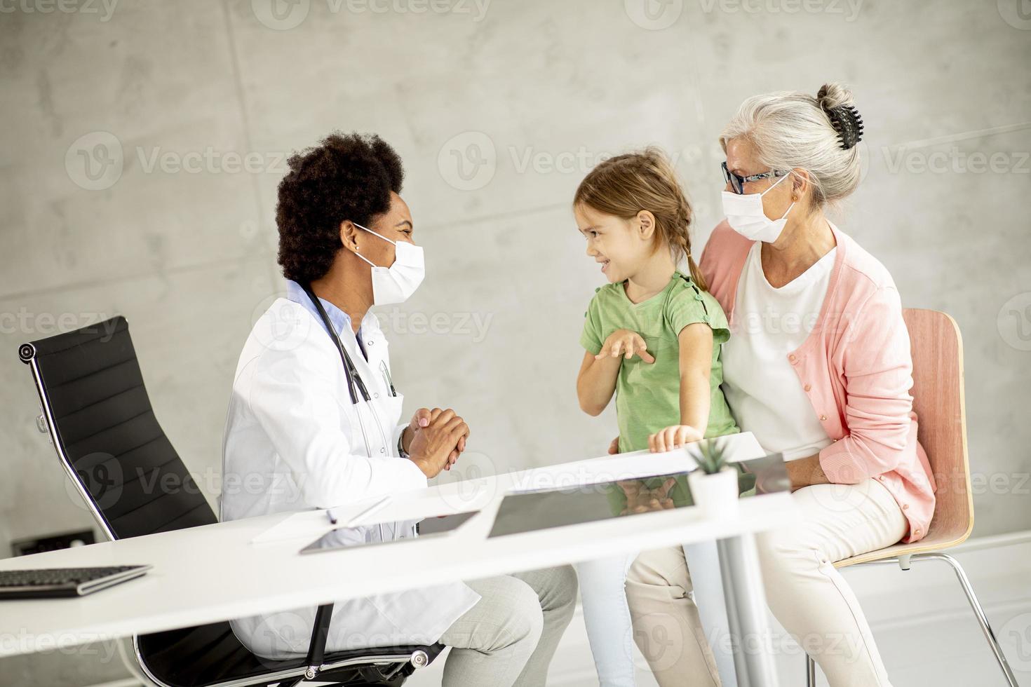 doctor hablando con niña con abuela foto
