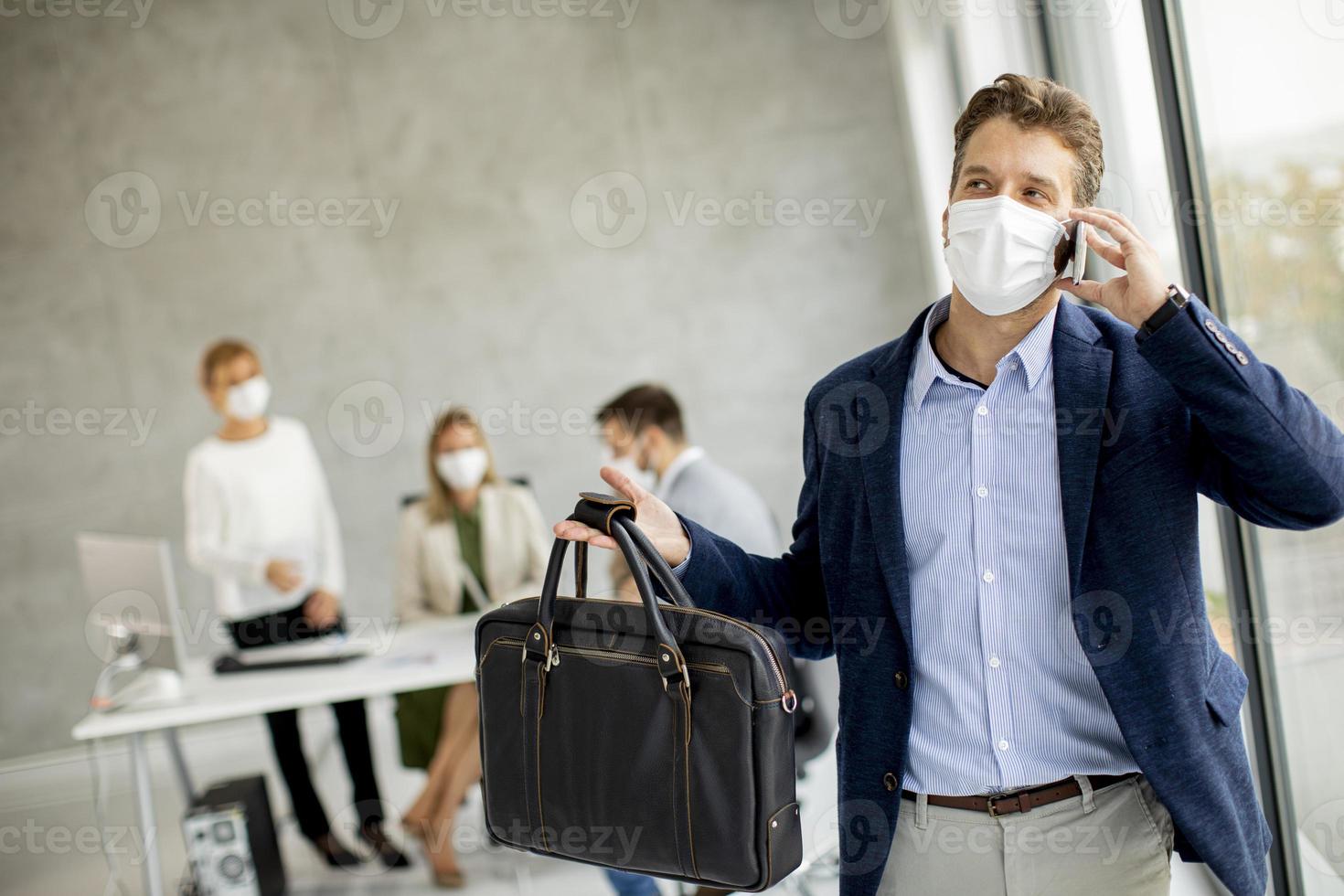 Businessman taking on phone with mask on photo