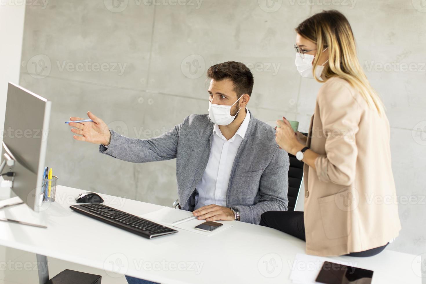 Masked professionals working at desk photo