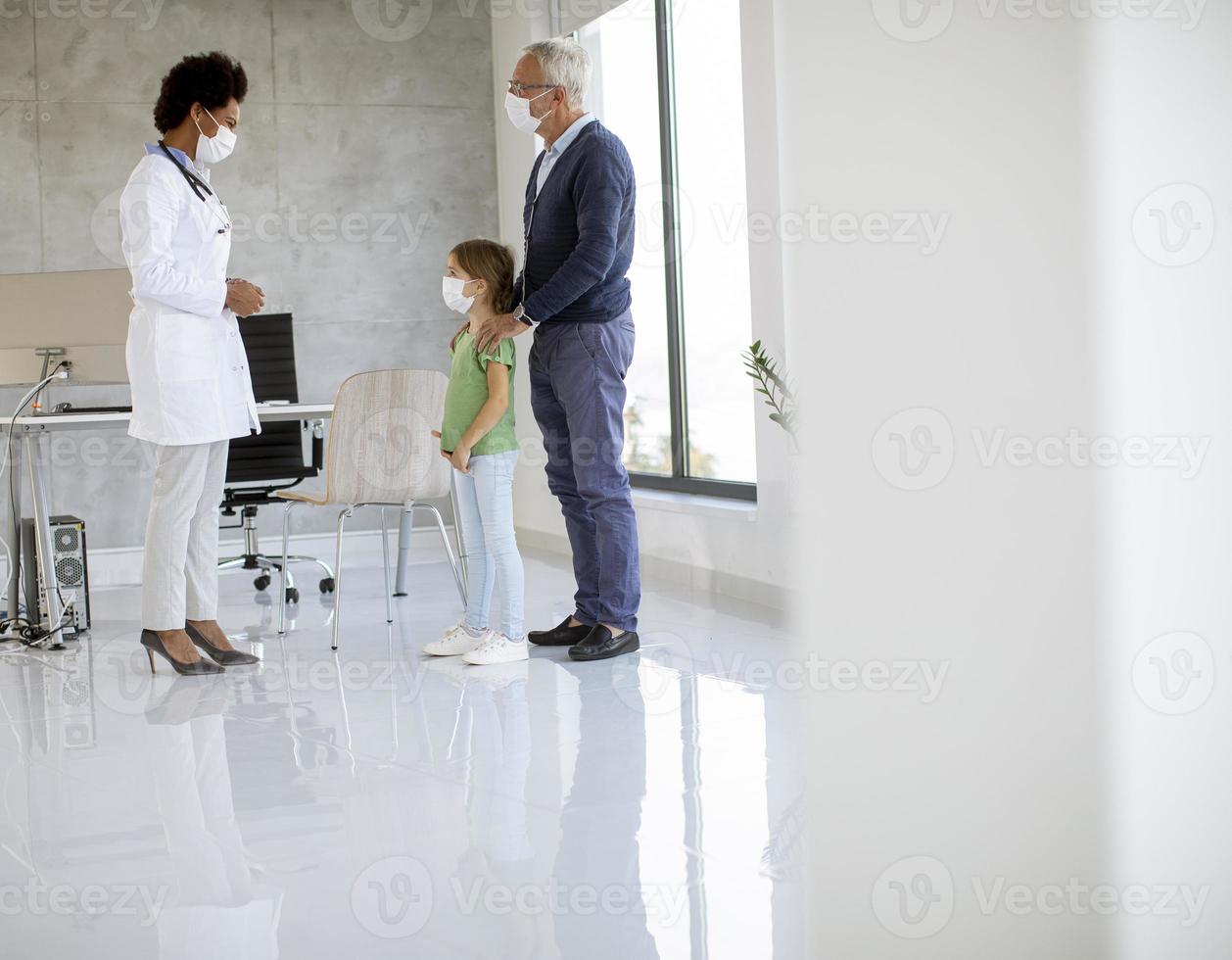 Granddaughter and grandfather in doctor's office with masks on photo