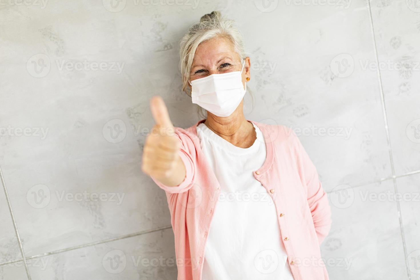 Masked mature woman giving a thumb's up photo