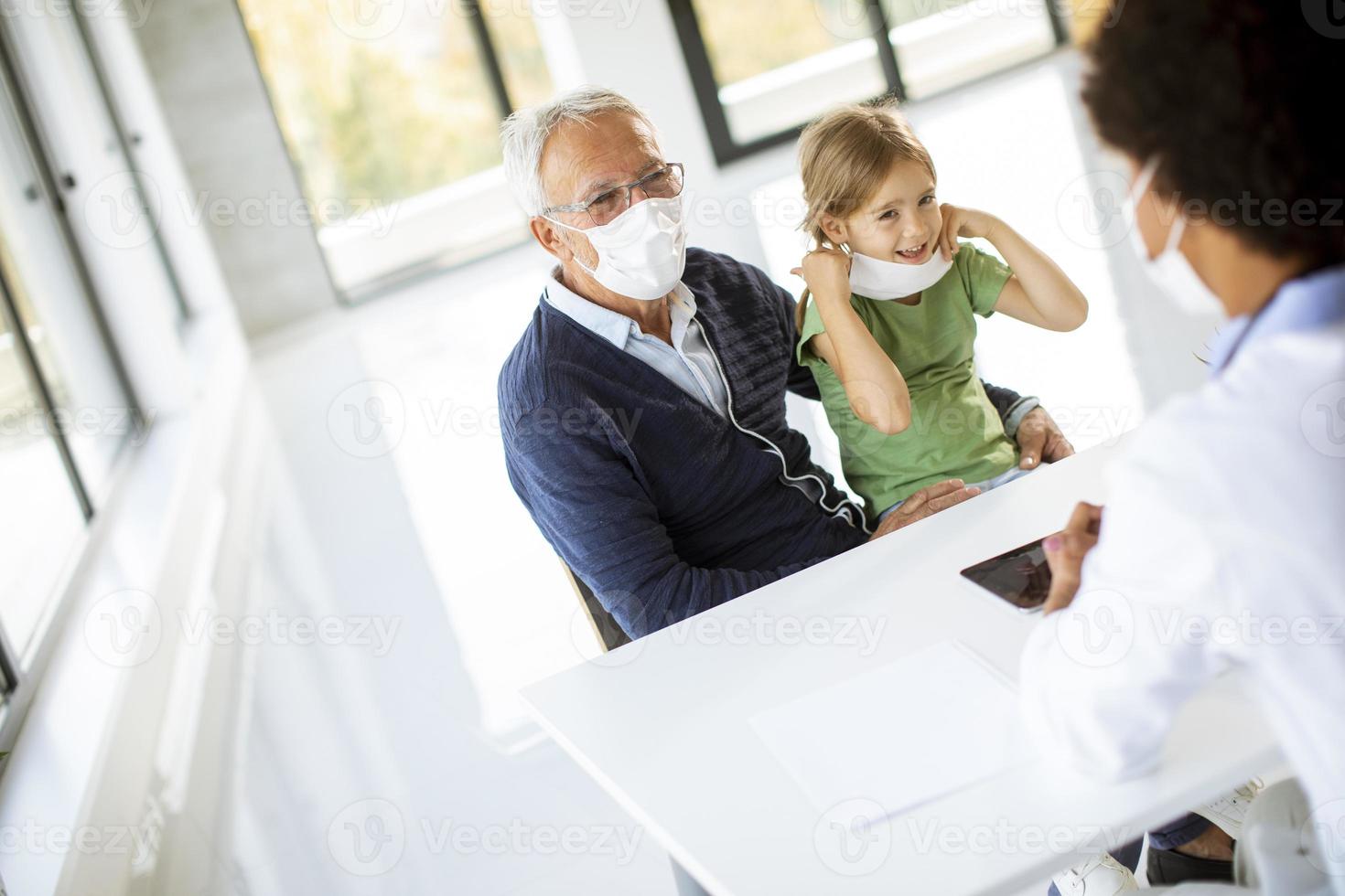 Grandfather and granddaughter in doctor's office with masks photo