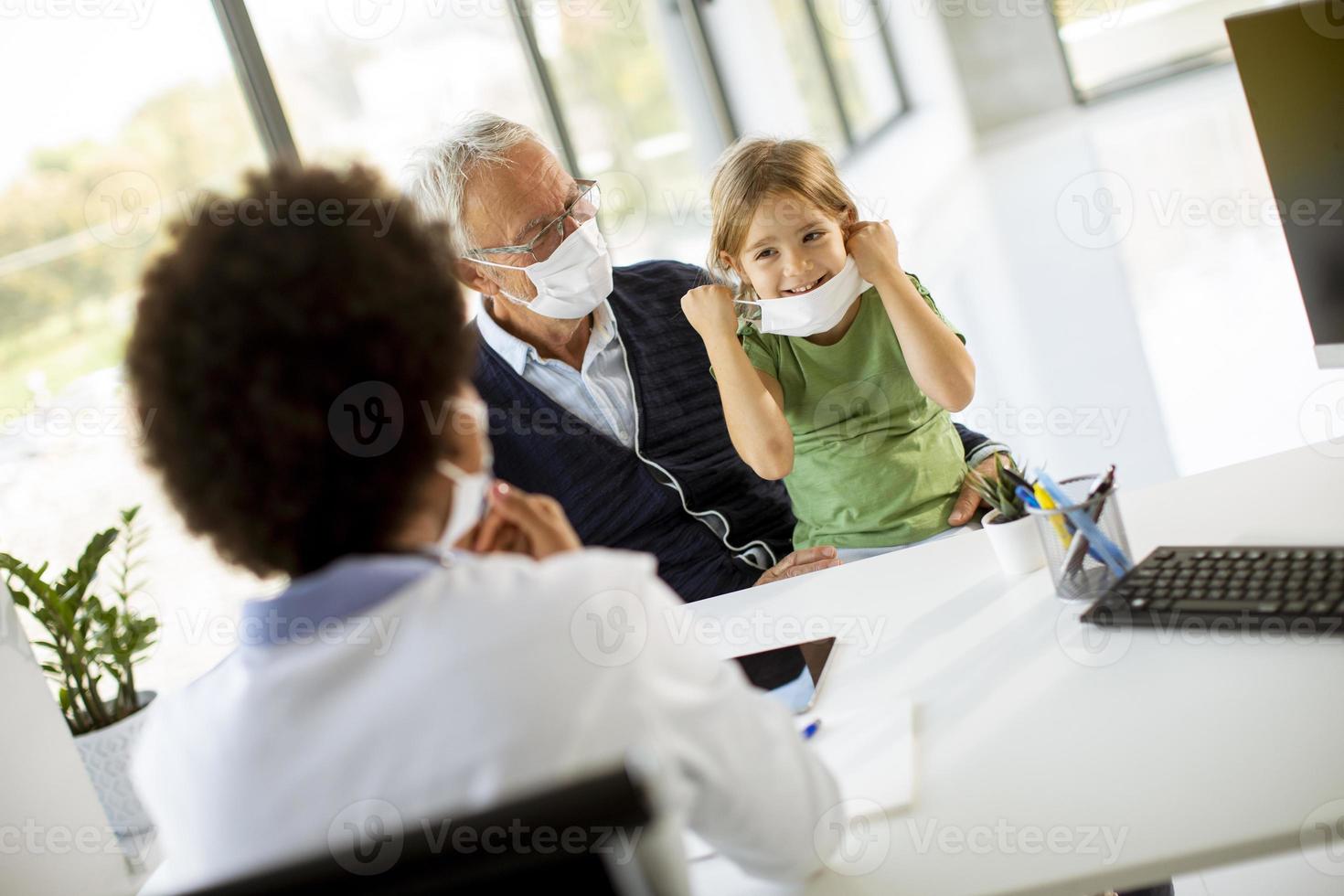 Grandfather and granddaughter in doctor's office with masks on photo