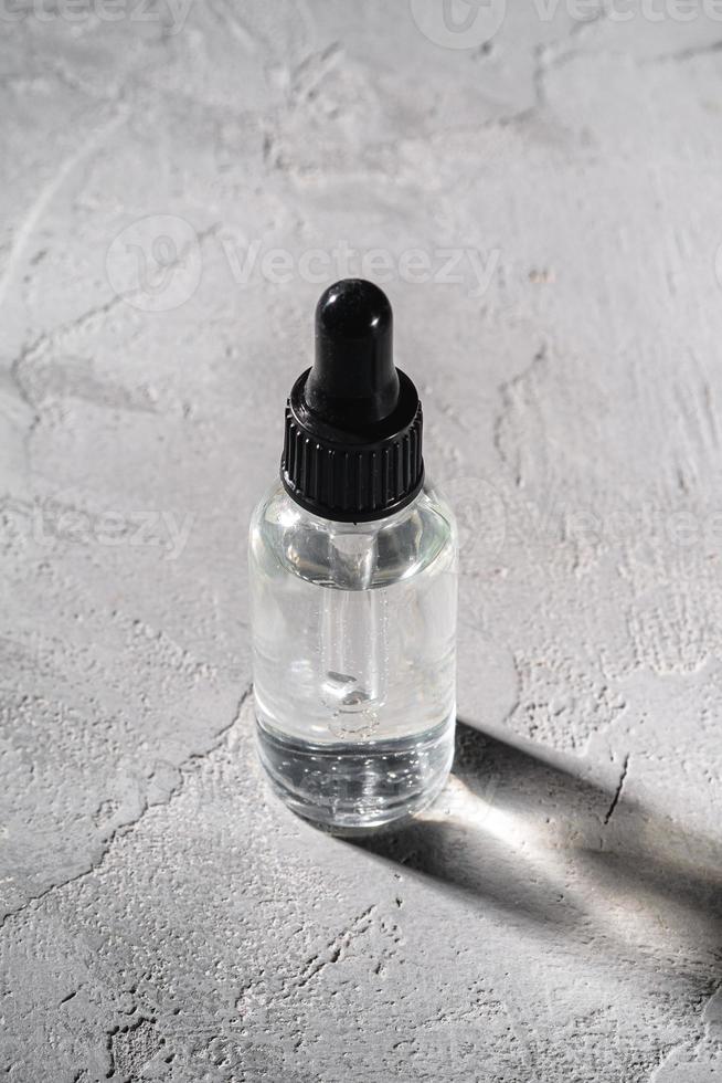 Skin care essence oil dropper in glass bottle on stone background photo