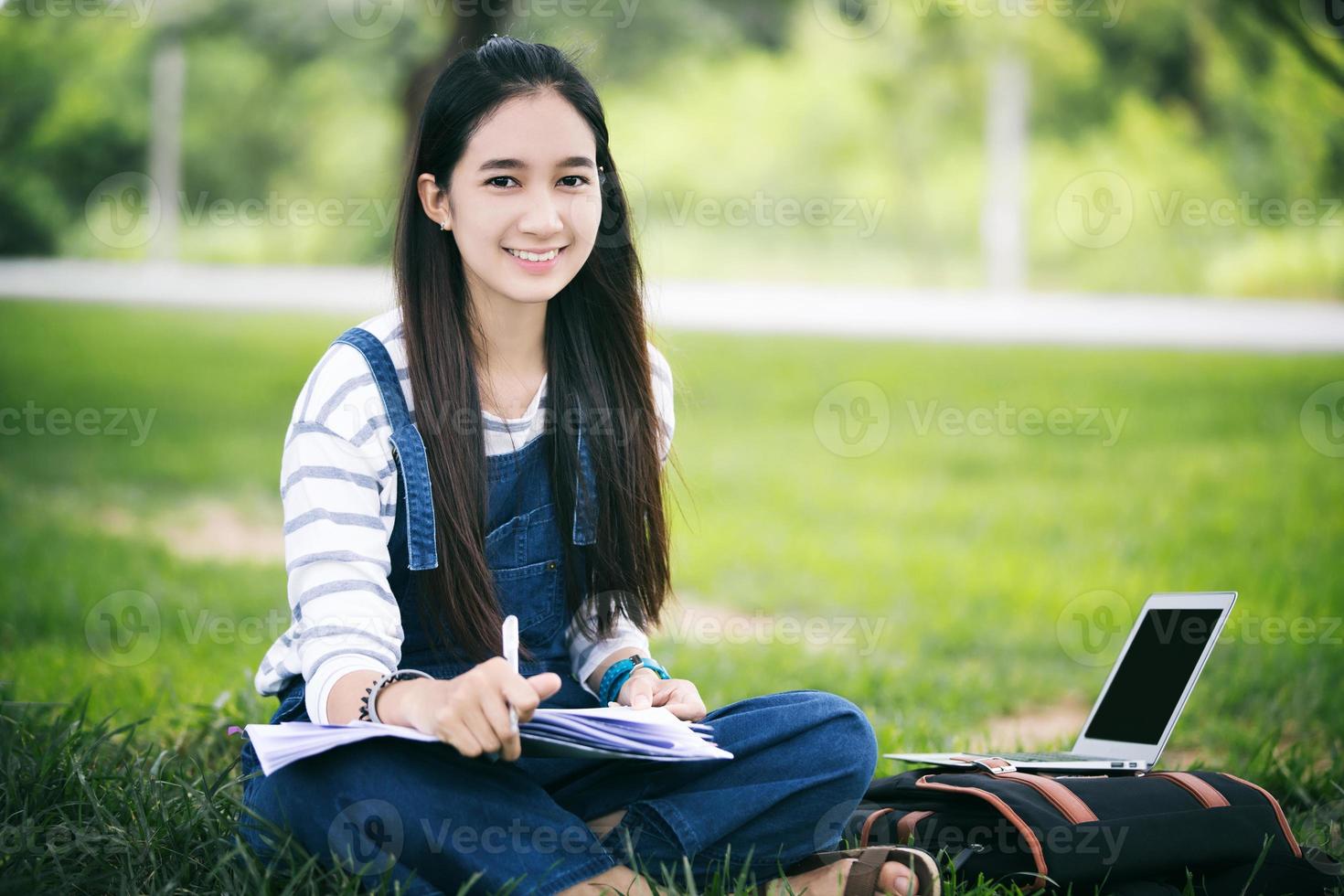estudiante sonriente que estudia afuera en el césped foto