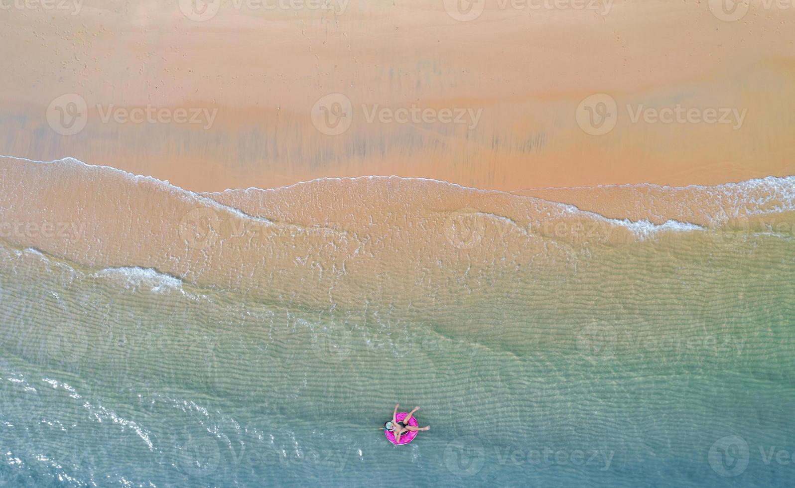 Aerial top view from drone View of boy with swim ring in the sea and shade emerald blue water and wave foam at sunrise photo