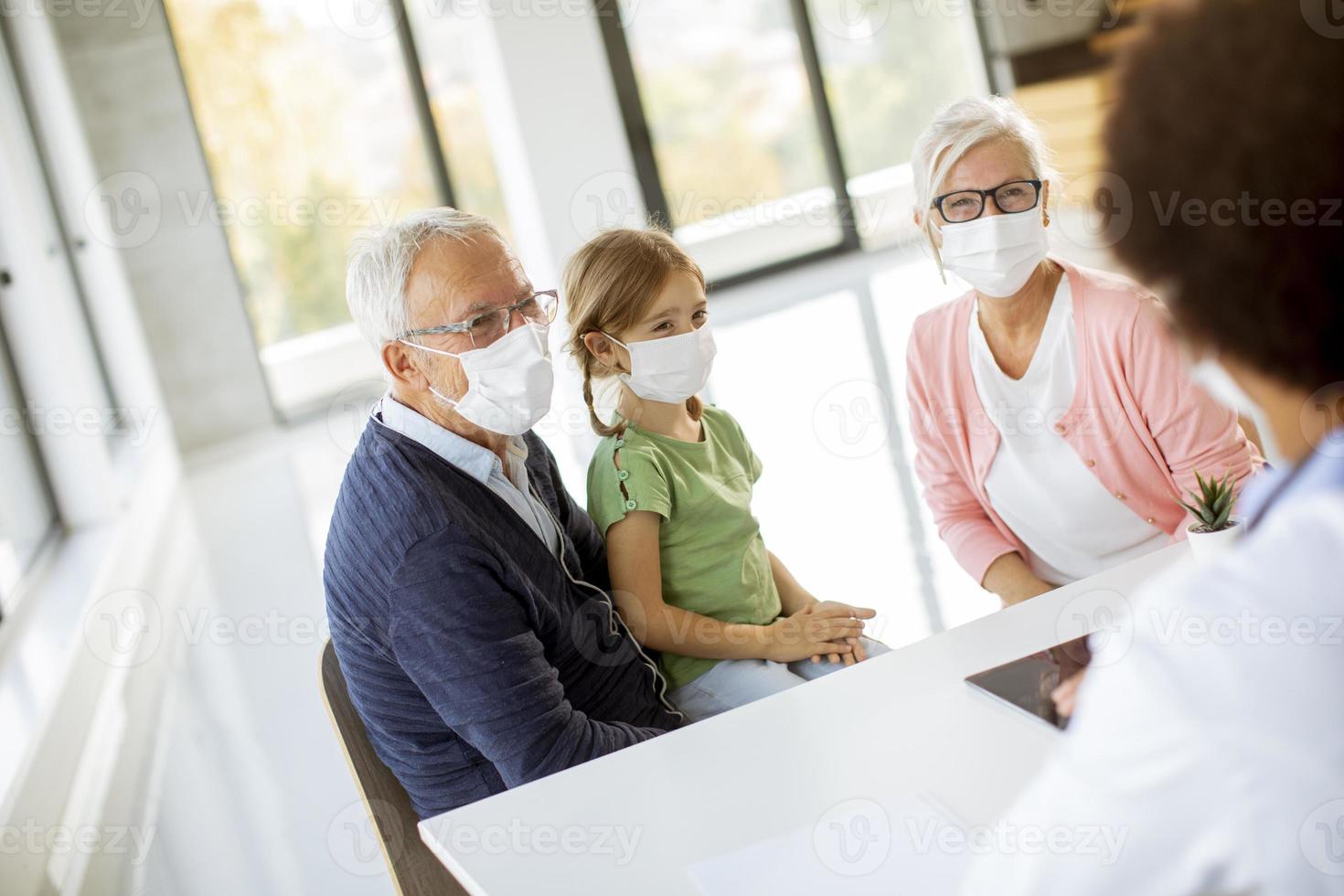 Grandparents with grandchild talking to a doctor photo