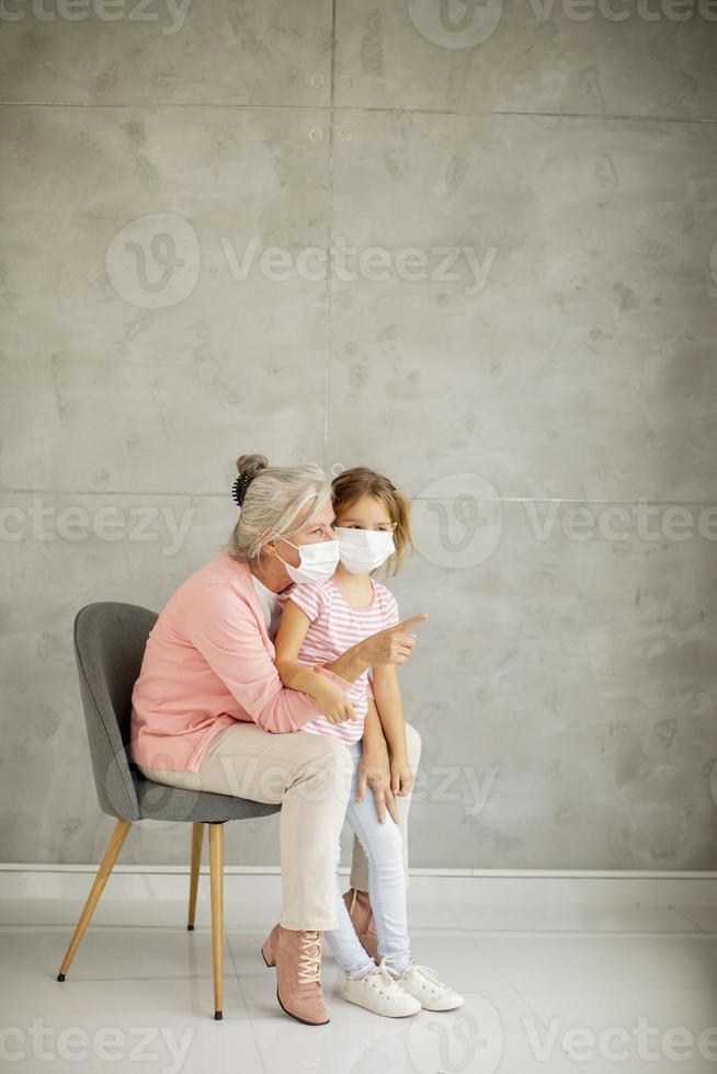 Grandmother talking to granddaughter wearing masks photo