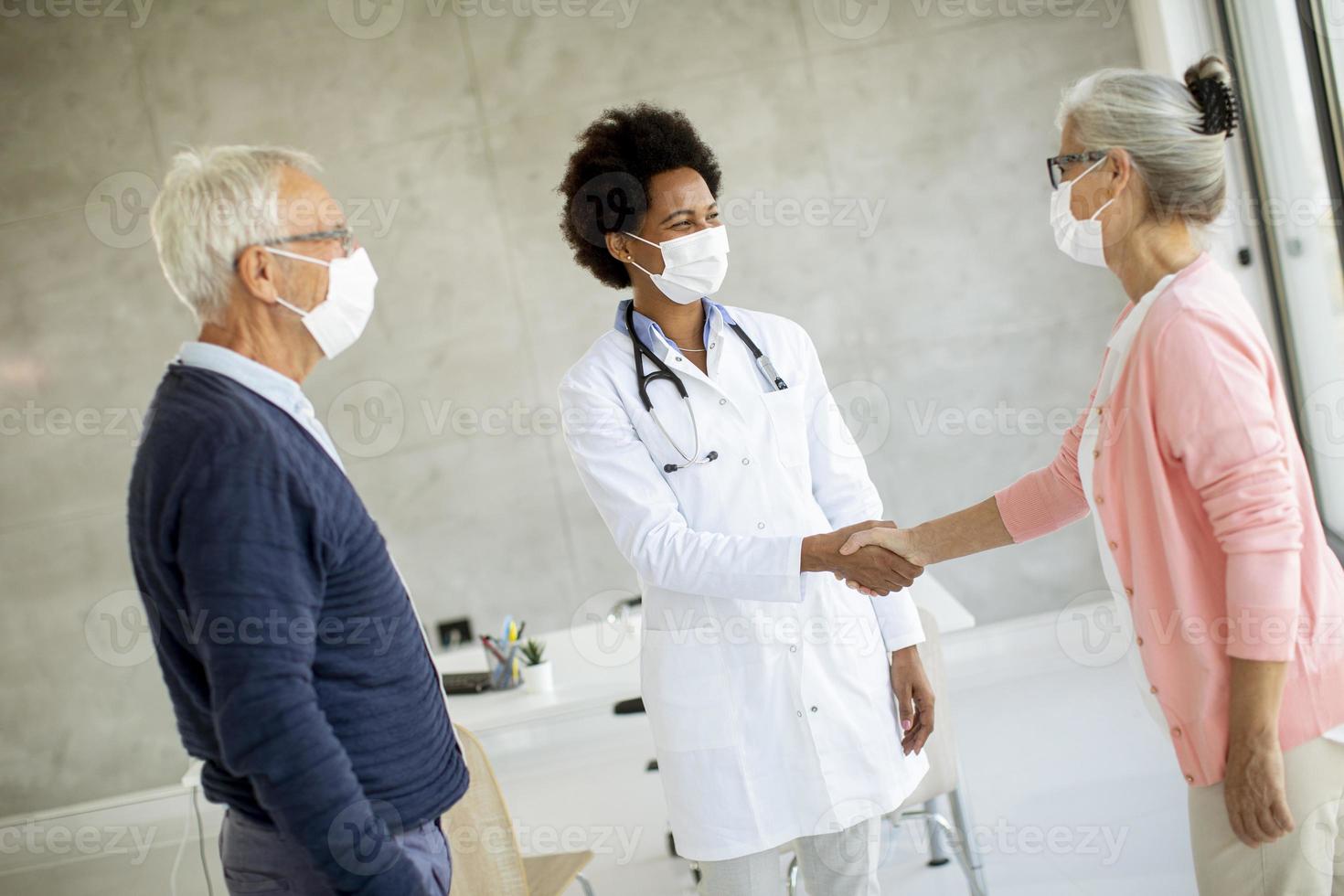 Doctor greeting senior couple photo
