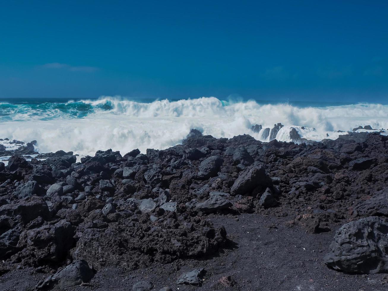 Olas que se encuentran con la costa volcánica negra en el golfo lanzarote islas canarias foto