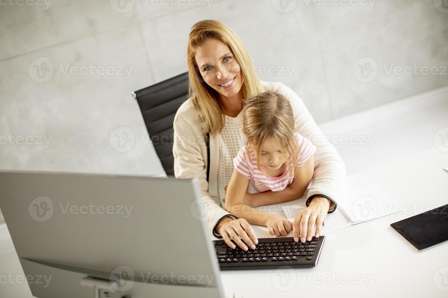 madre trabajando con hija en el regazo foto