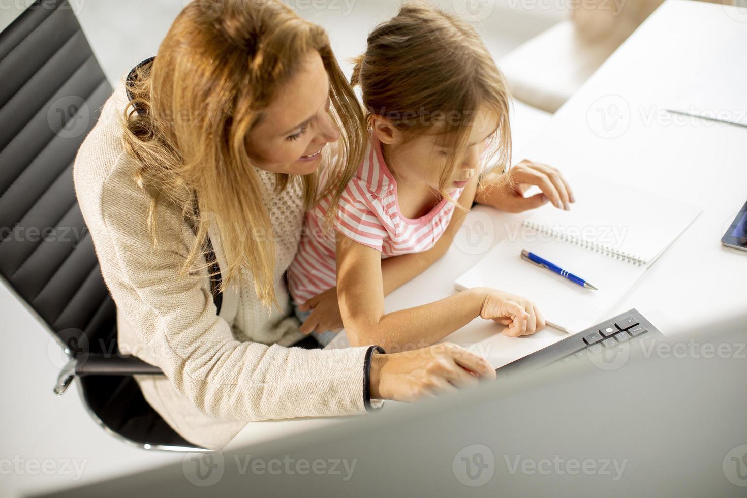 Vista superior de una madre que trabaja con su hija en su regazo foto