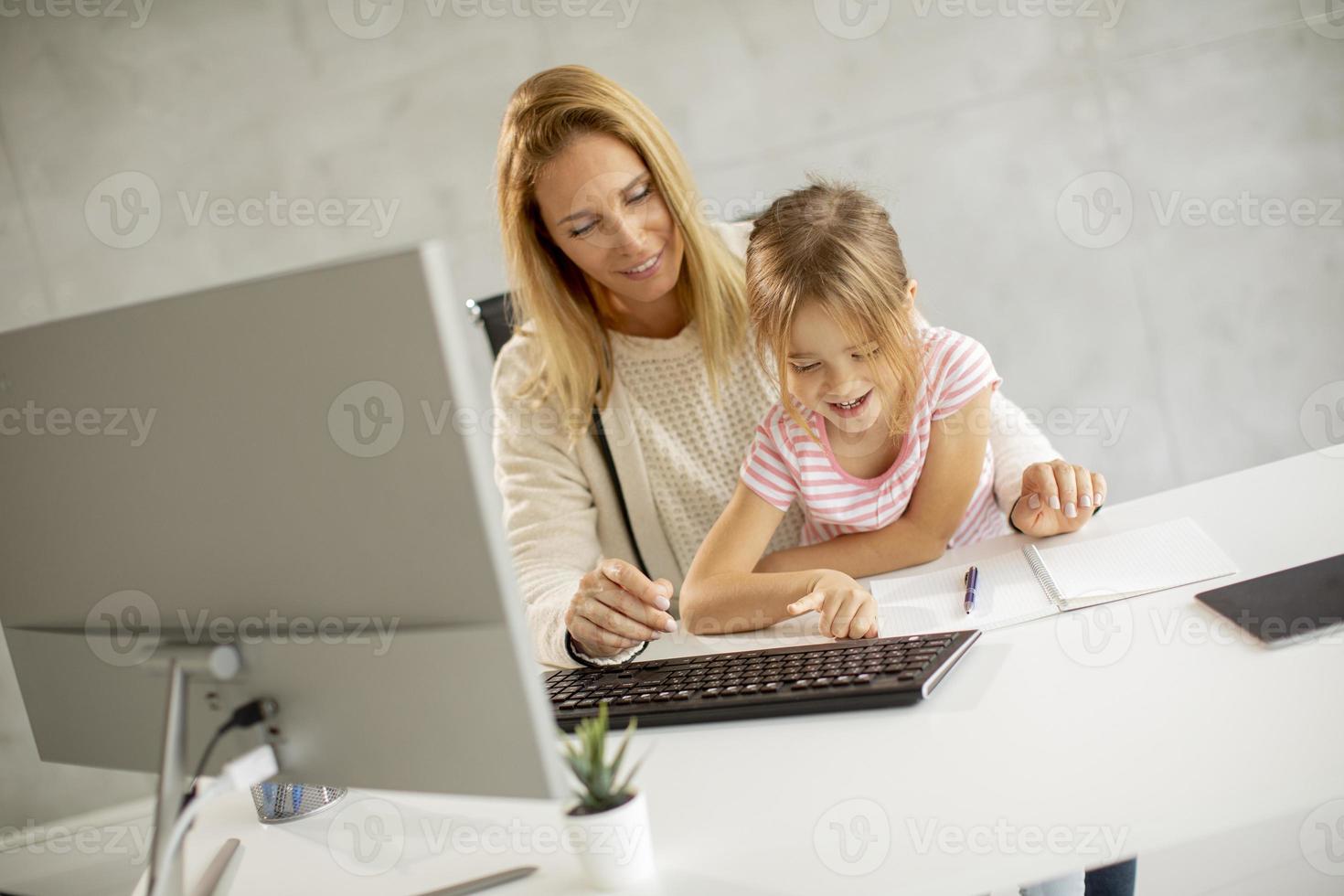 madre trabajando con hija en su regazo foto