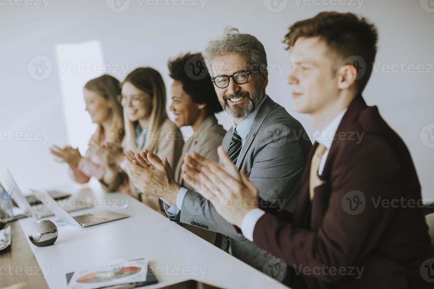 La gente de negocios aplaudiendo con el hombre mirando a la cámara foto