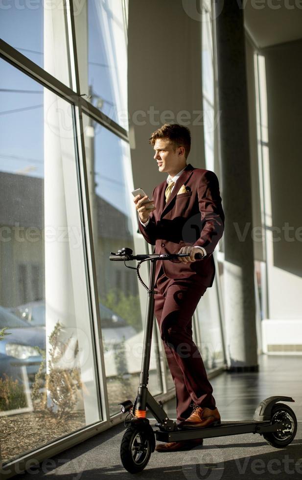 Vertical view of a businessman on a scooter on a phone photo