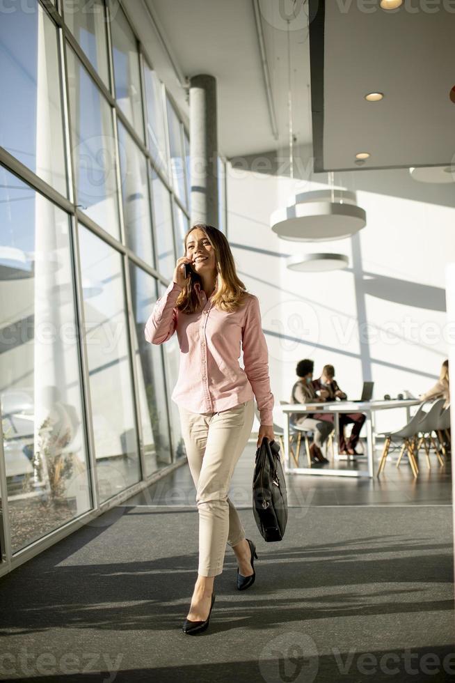 Businesswoman on cell phone walking in the office photo