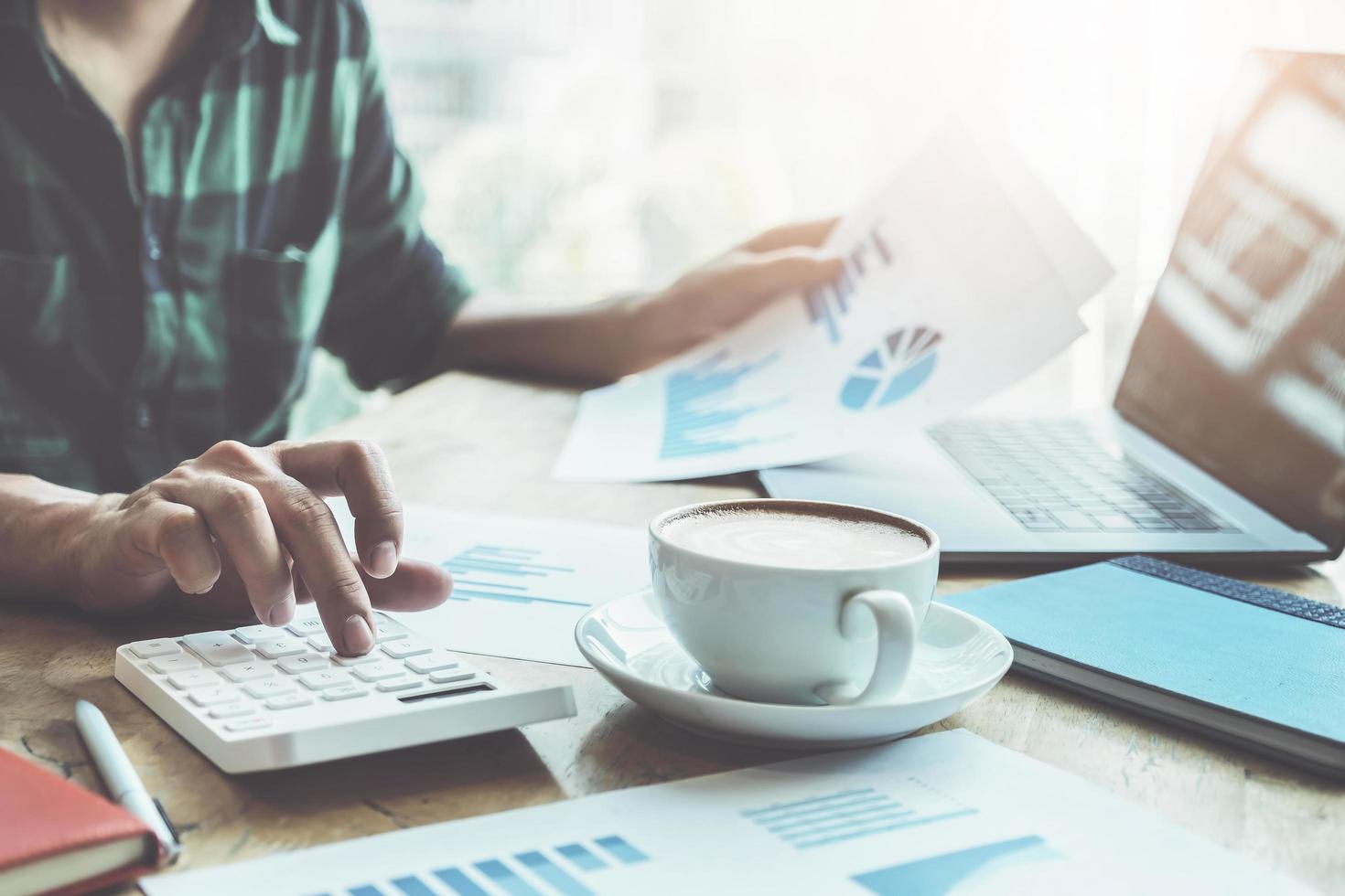 The accountant is pressing the calculator to calculating check the accuracy of the investment budget with using computer laptop and document data to analysis photo