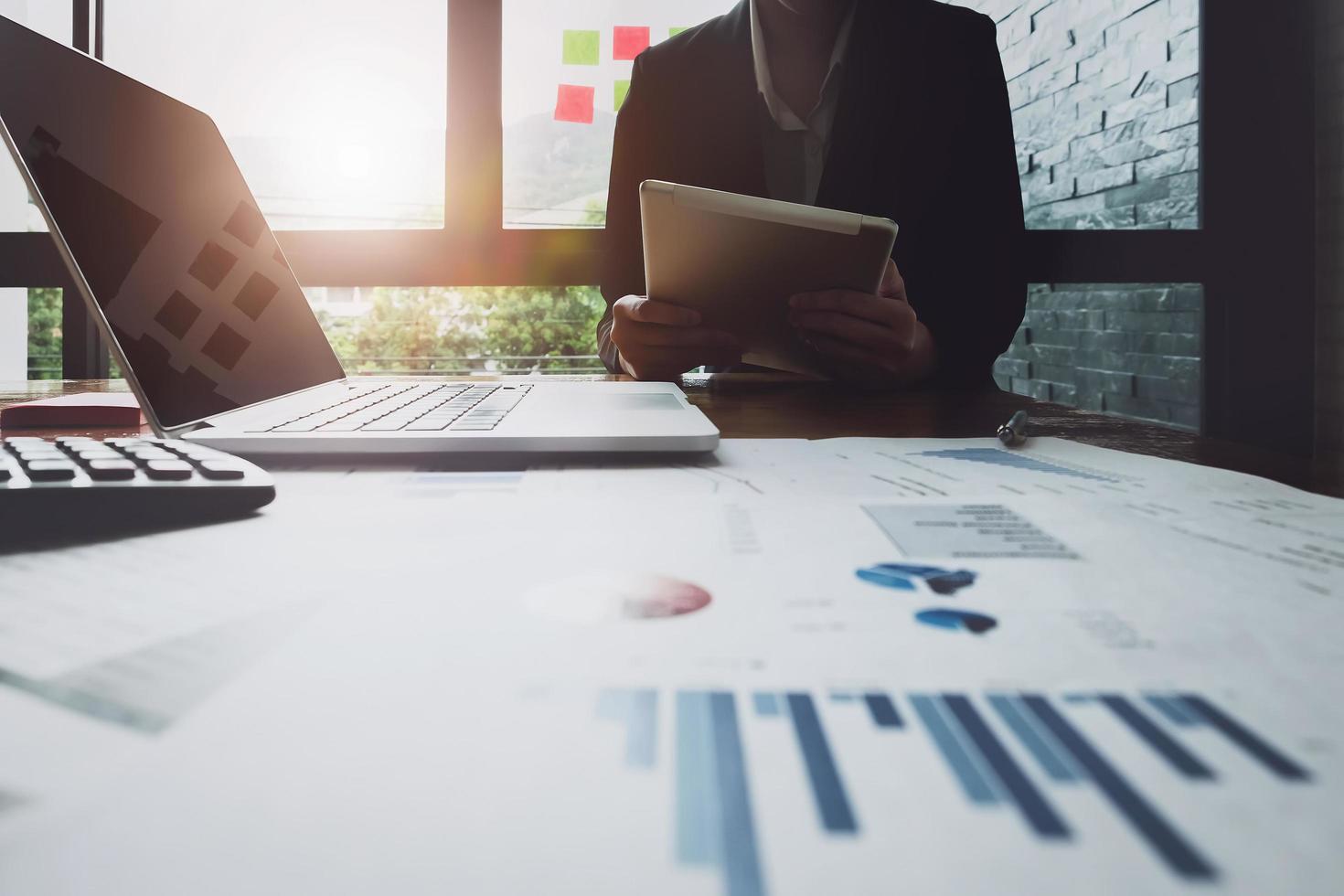 Mujer de negocios analizando tablas y gráficos de ingresos para planificar el concepto de marketing con el uso de una tableta y una computadora para el análisis foto