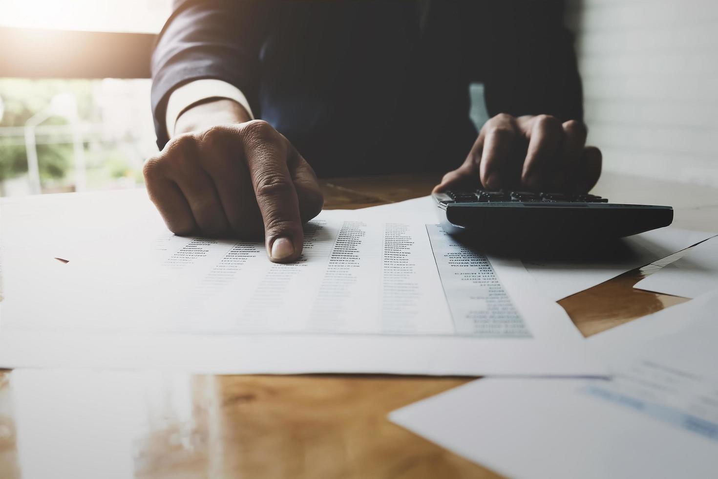 Hombre de negocios usando la calculadora con calcular el gráfico de datos del mercado de valores y el papel de impuestos y presupuestos en la oficina foto