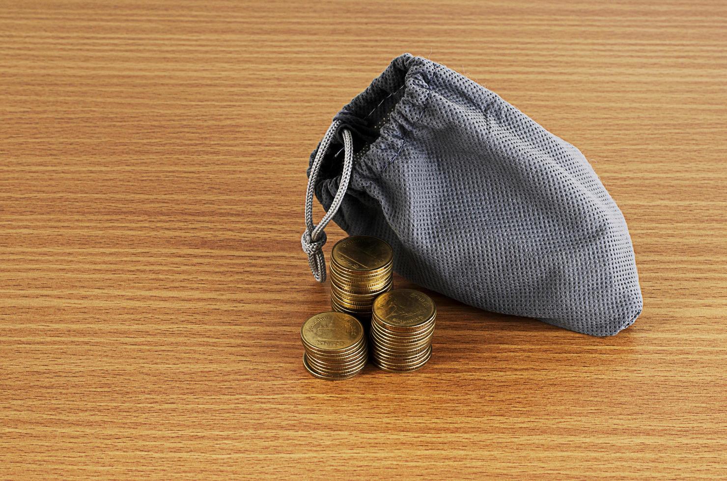 Coins stack and money bag on wooden table background. photo