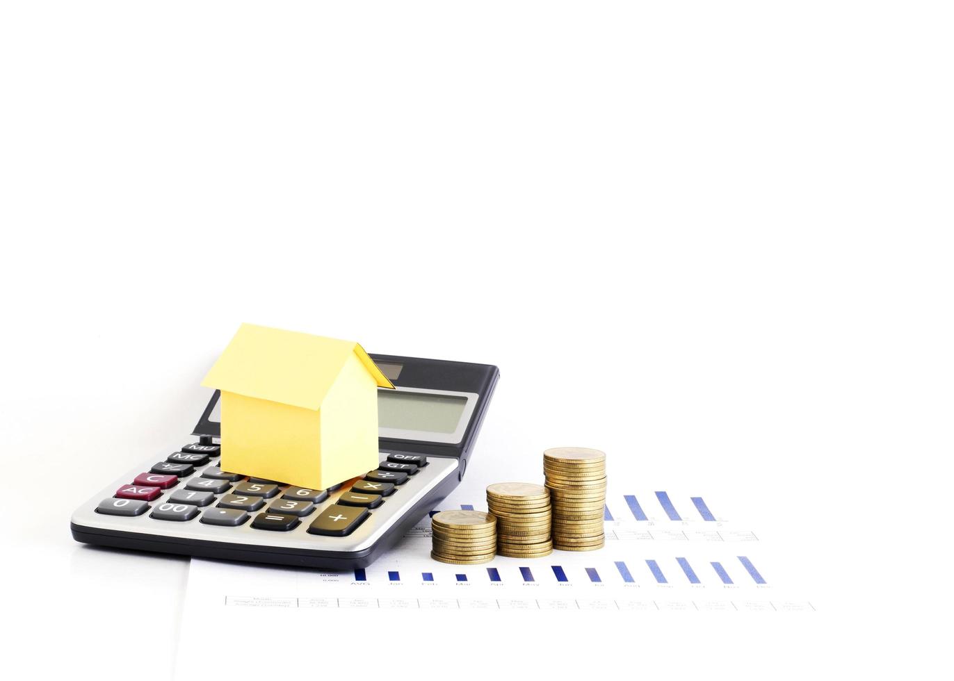 Calculadora y pila de monedas de dinero con papel de la casa para el concepto de préstamo foto