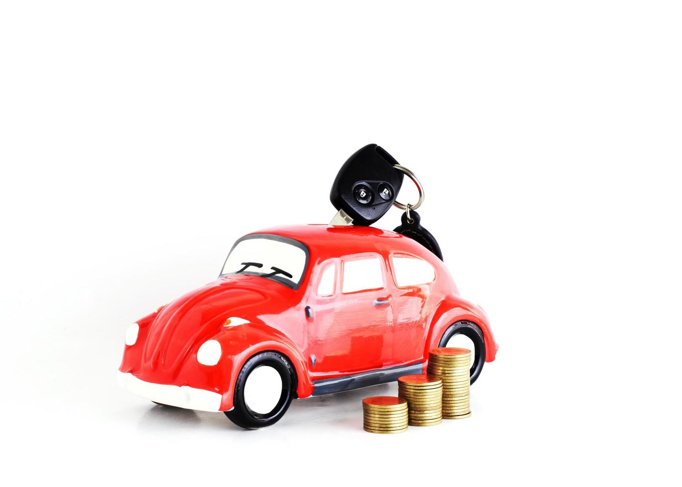 Car key into car bank and coins stack on white background for loans concept photo