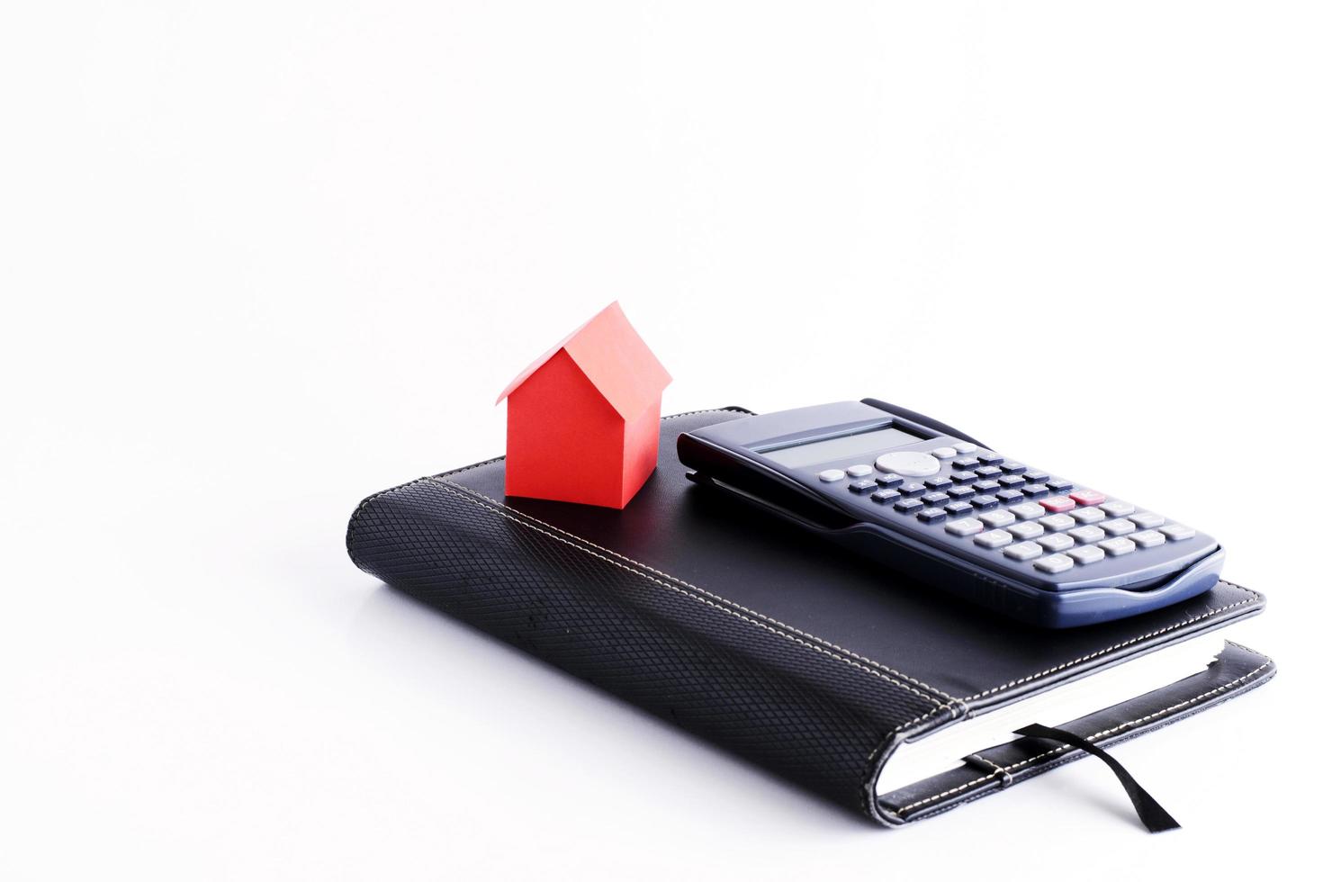 Red house paper and calculator on business book on white background photo