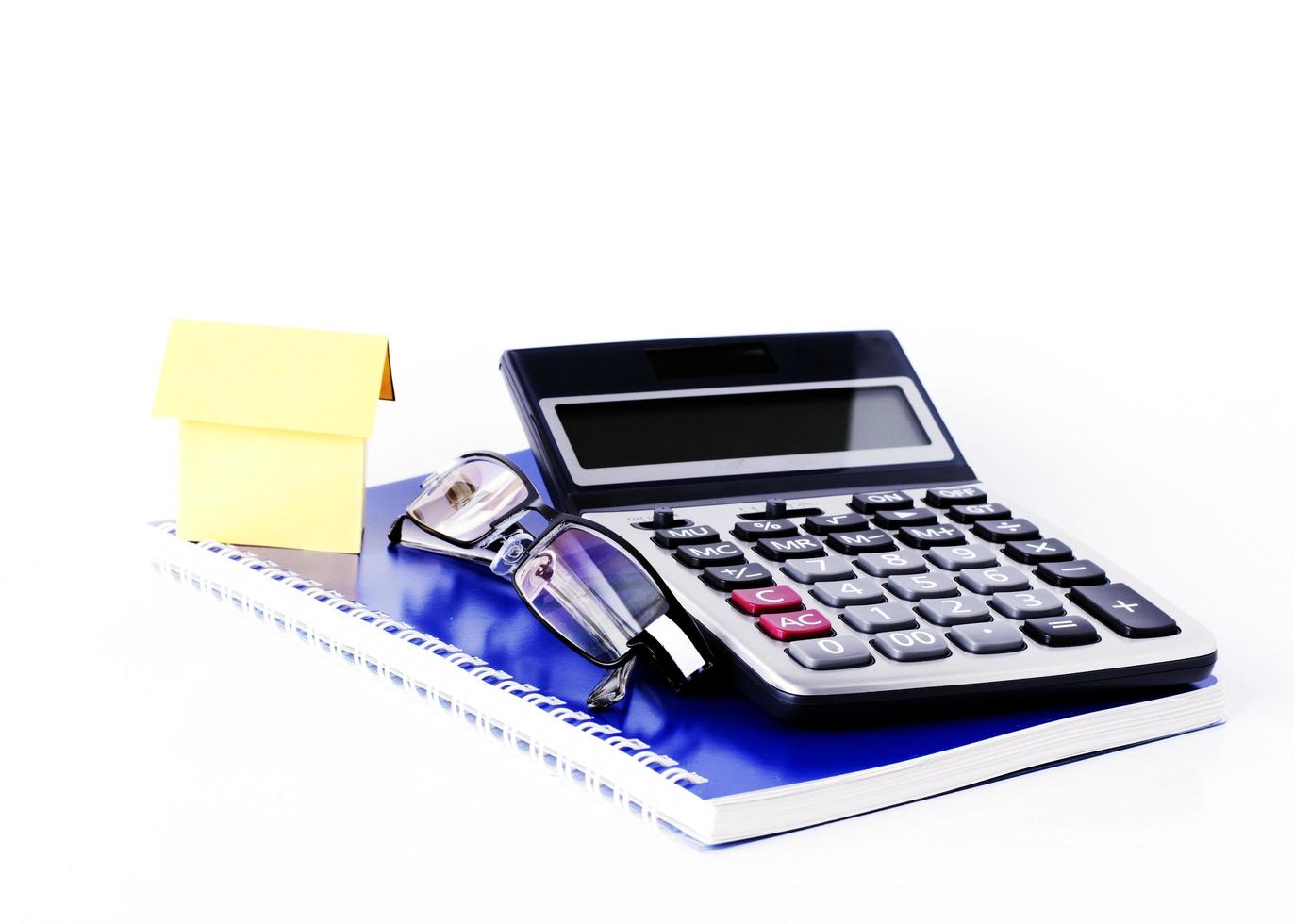 Paper house and eyeglasses and calculator on notebook for business concept background photo